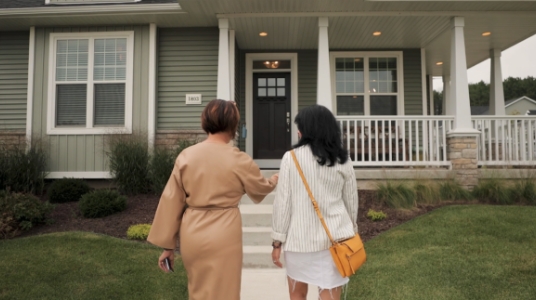 An agent approaches a home with her client